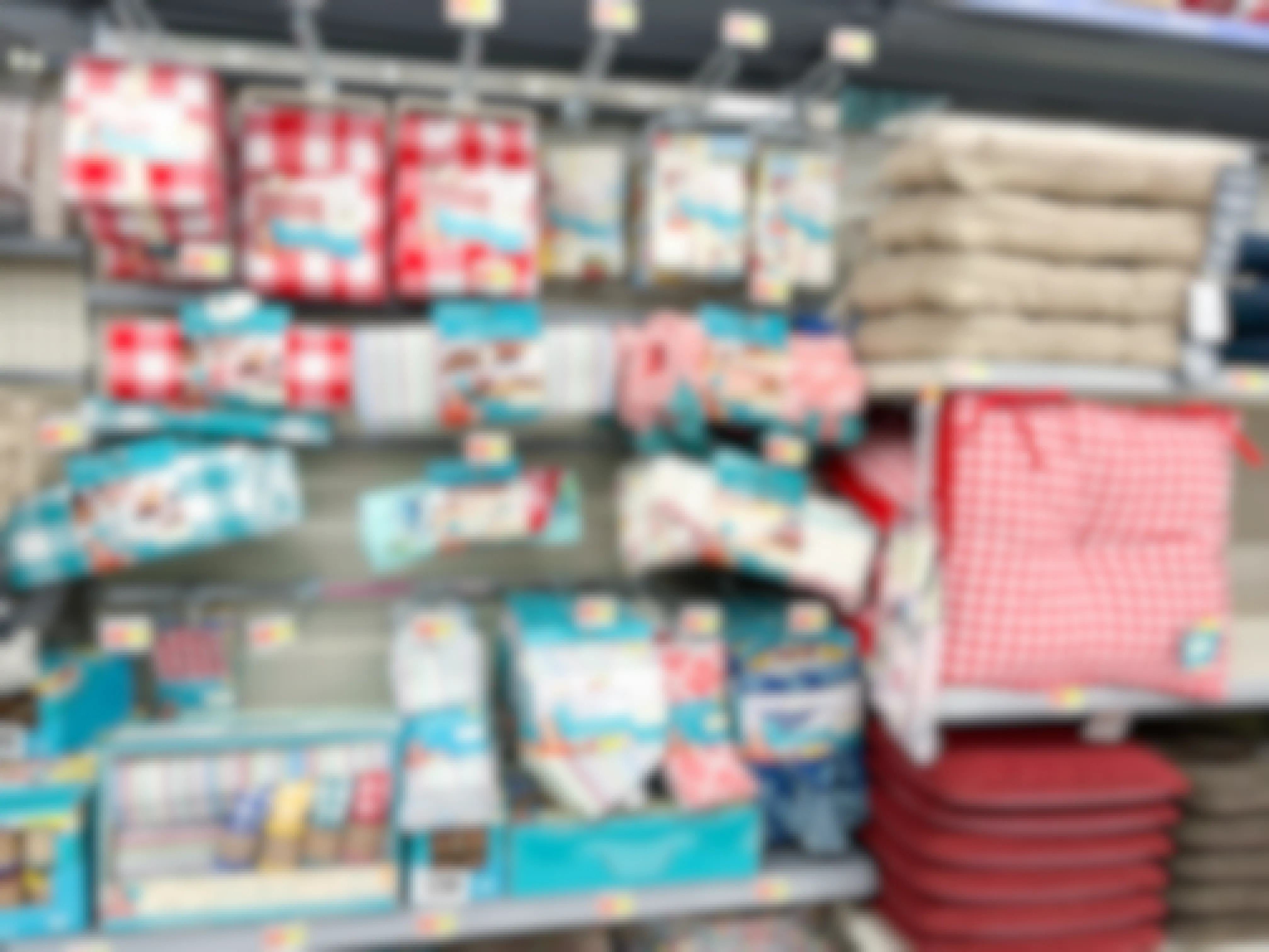 A walmart shelf filled with The Pioneer Woman kitchen and home items, including dish towels, chair cushions, and more