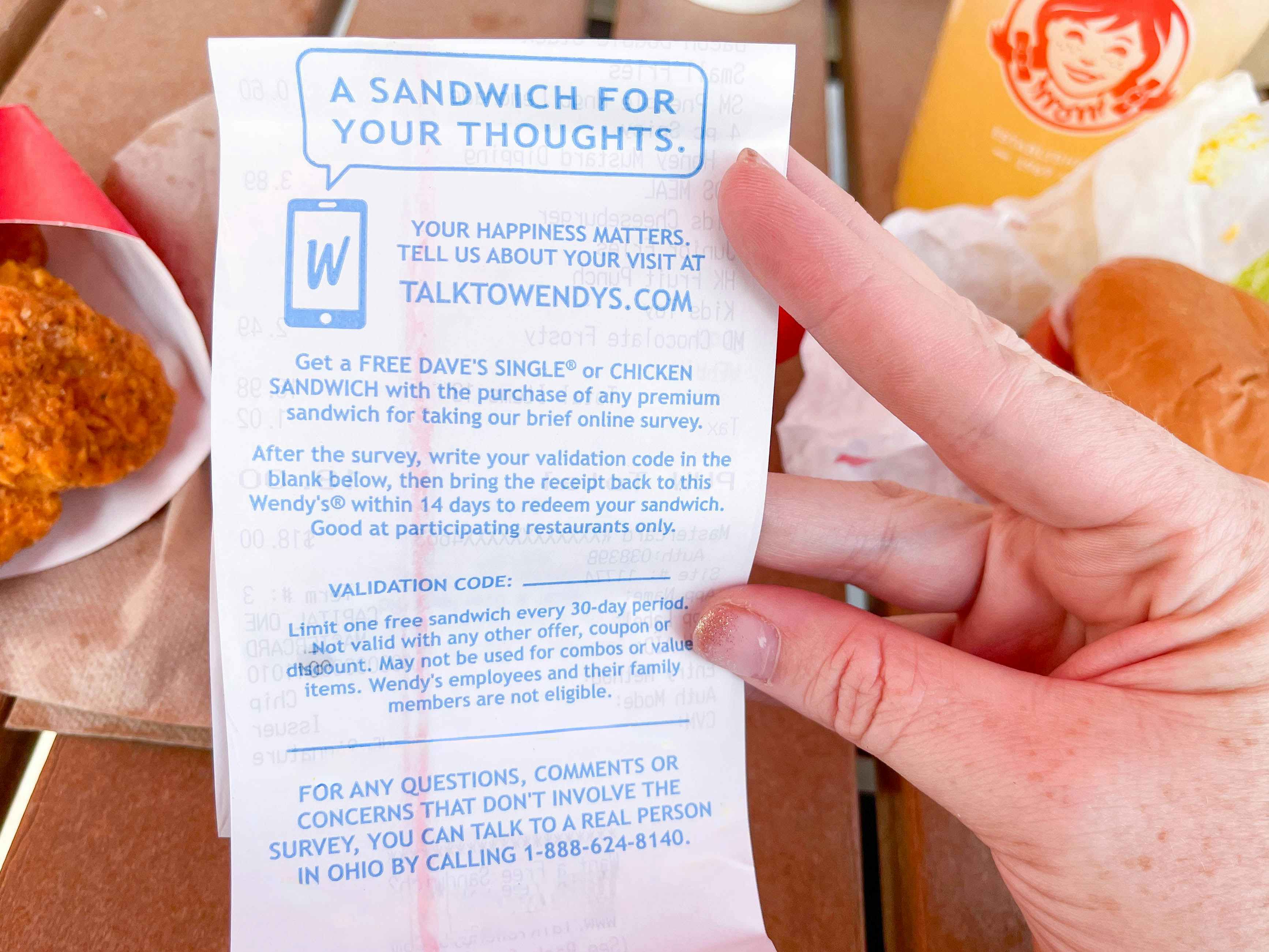 someone holding a wendys receipt with survey info