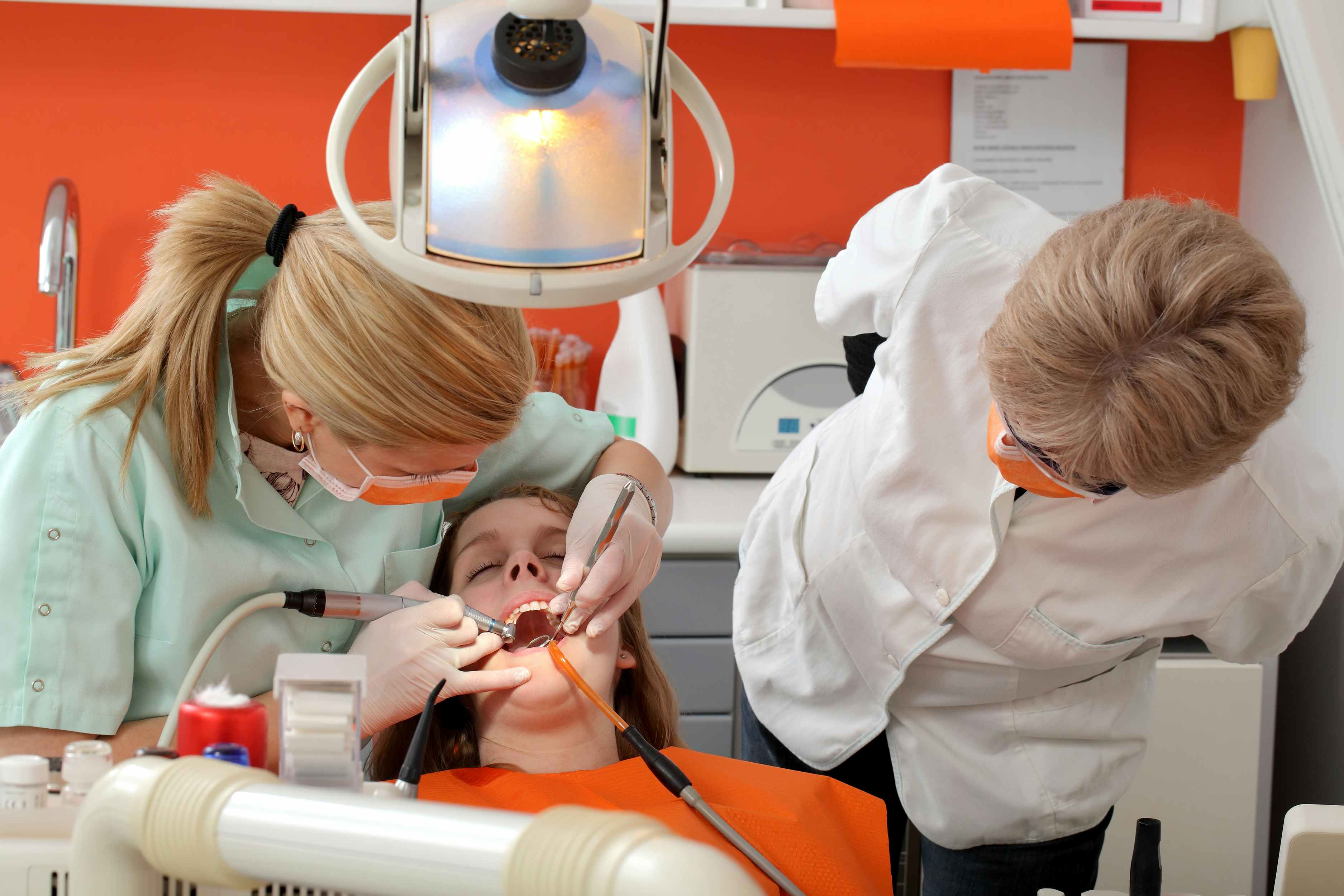 A dental school student doing a teeth cleaning under the supervision of an instructor