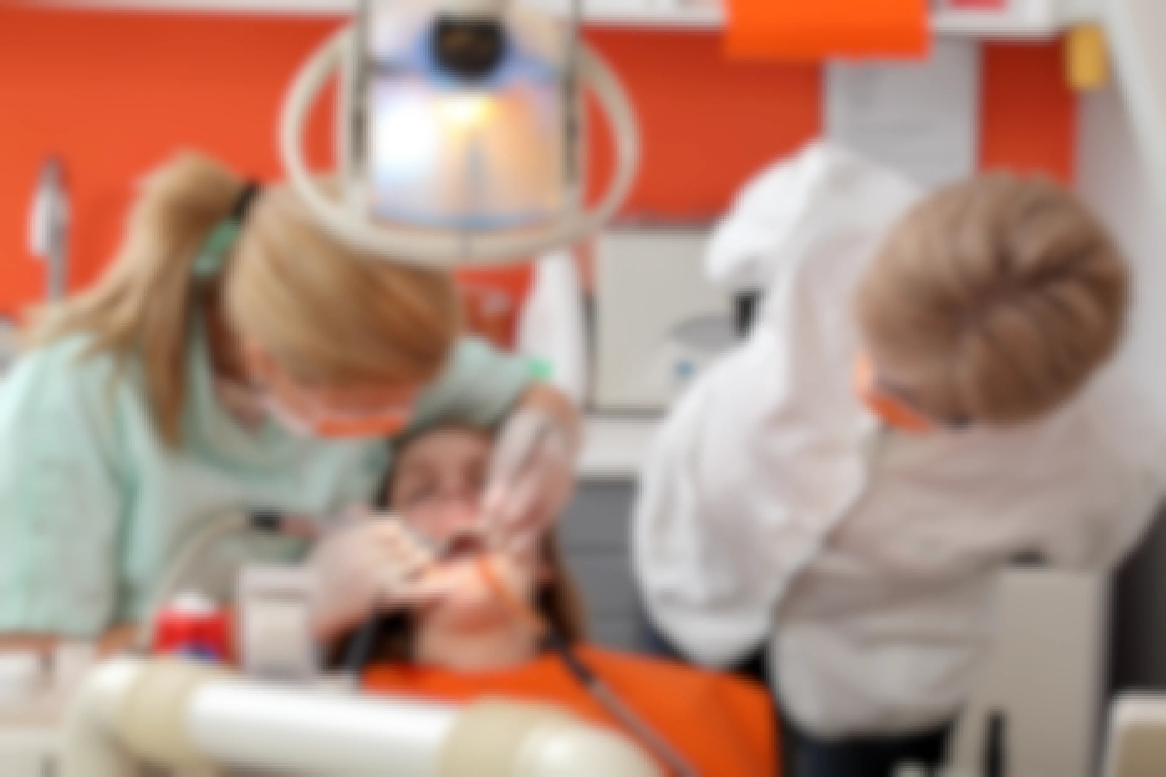 A dental school student doing a teeth cleaning under the supervision of an instructor