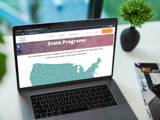 A laptop displaying the Dental Lifeline Network's website page for State Programs and a map