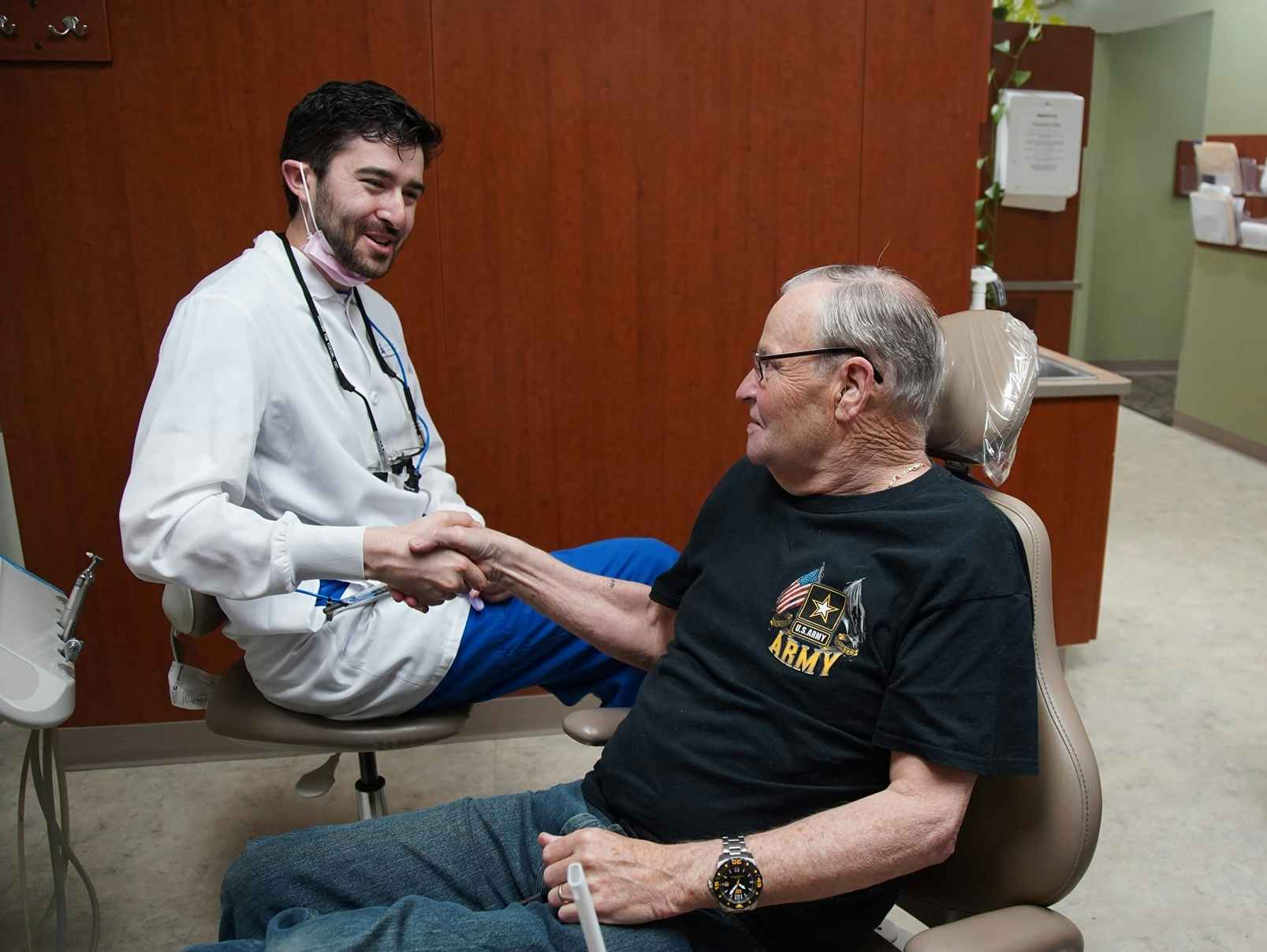 A dentist shaking the hand of a military veteran in sitting in their office