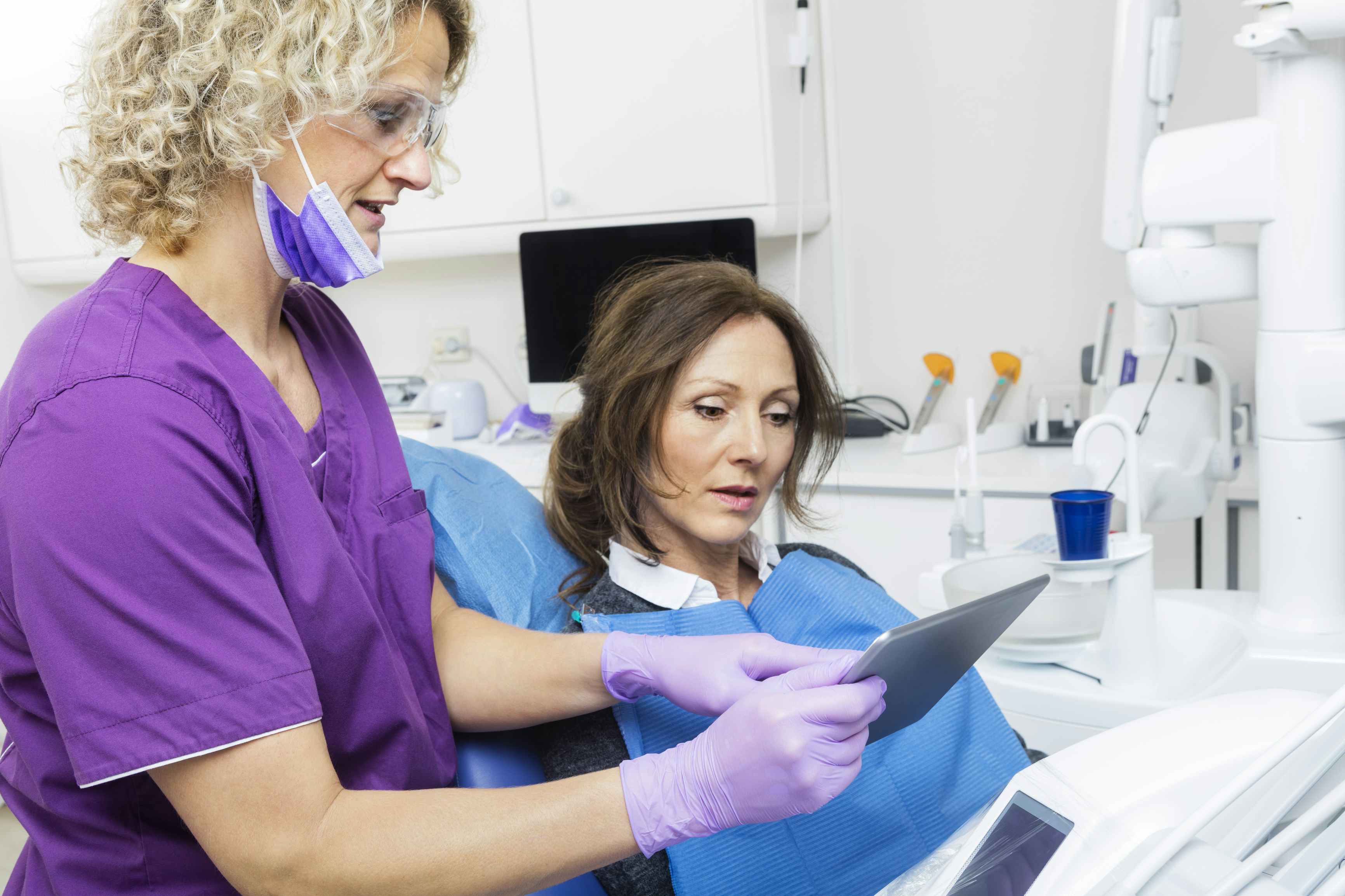 A dentist showing a patient something on a tablet