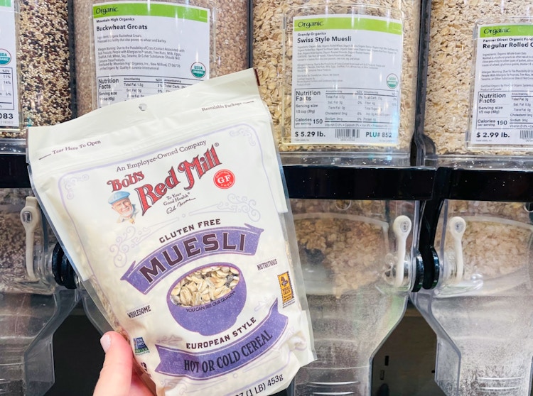 Someone holding some prepackaged food in front of a bulk container at Whole Foods