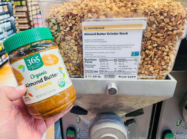 Someone holding some prepackaged food in front of a bulk container at Whole Foods