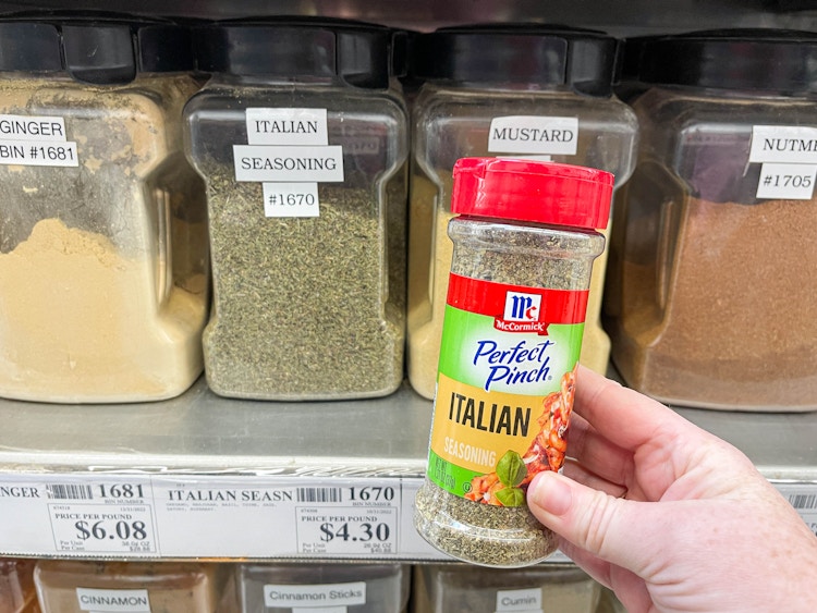 a bottle of itallian seasoning being held in fromt of winco bulk spices