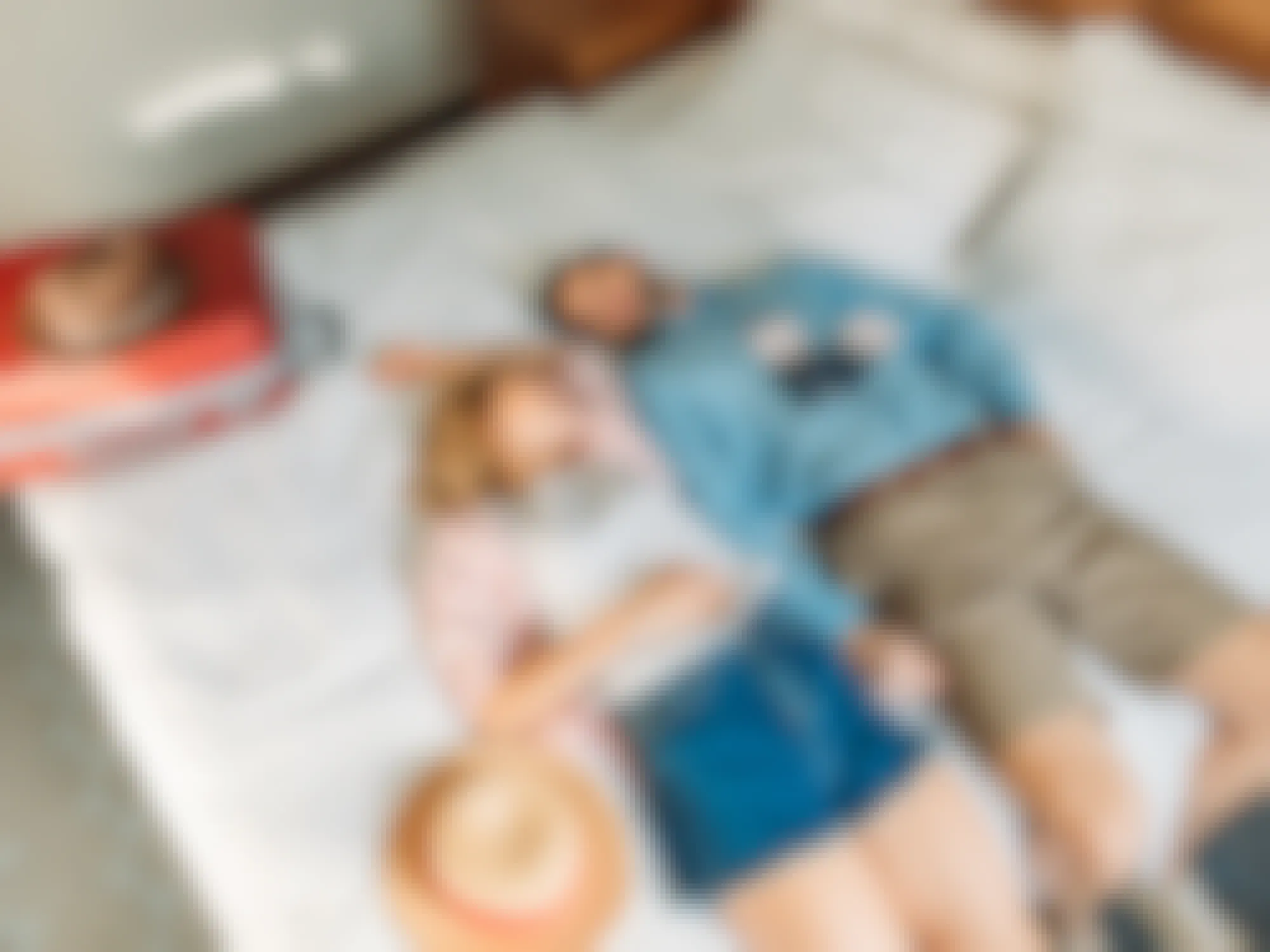happy young couple lying on hotel bed with suitcase