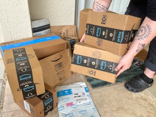 Someone picking up Amazon prime boxes on the porch