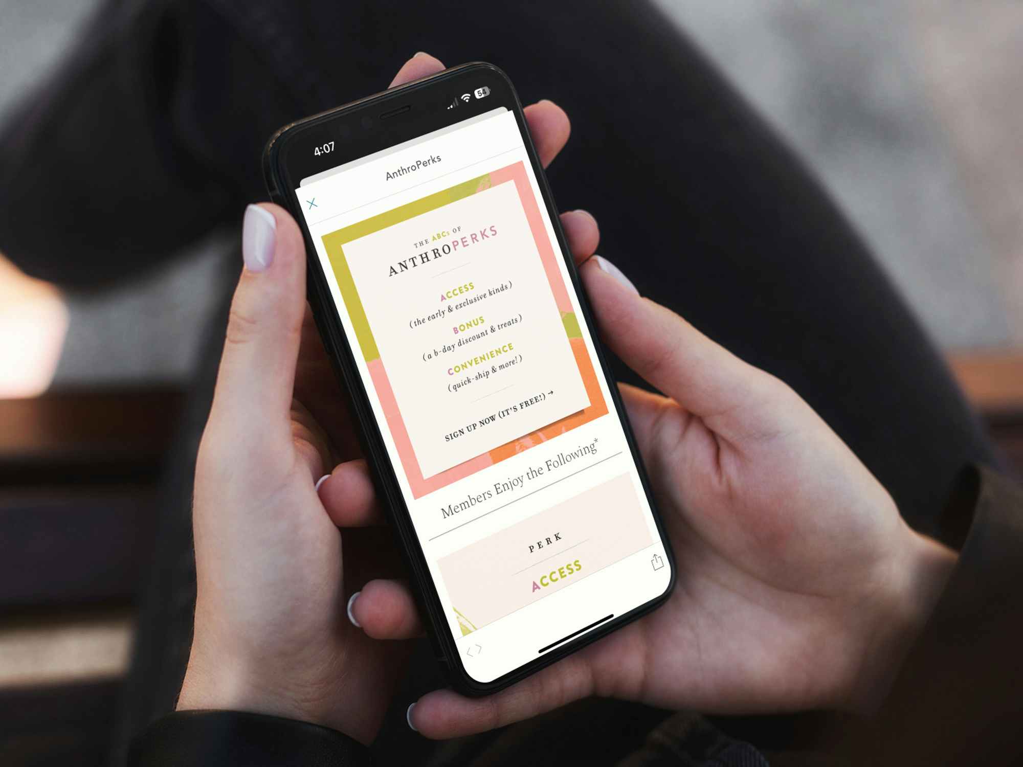 Someone holding a phone displaying Anthroperks information on the Anthropologie app