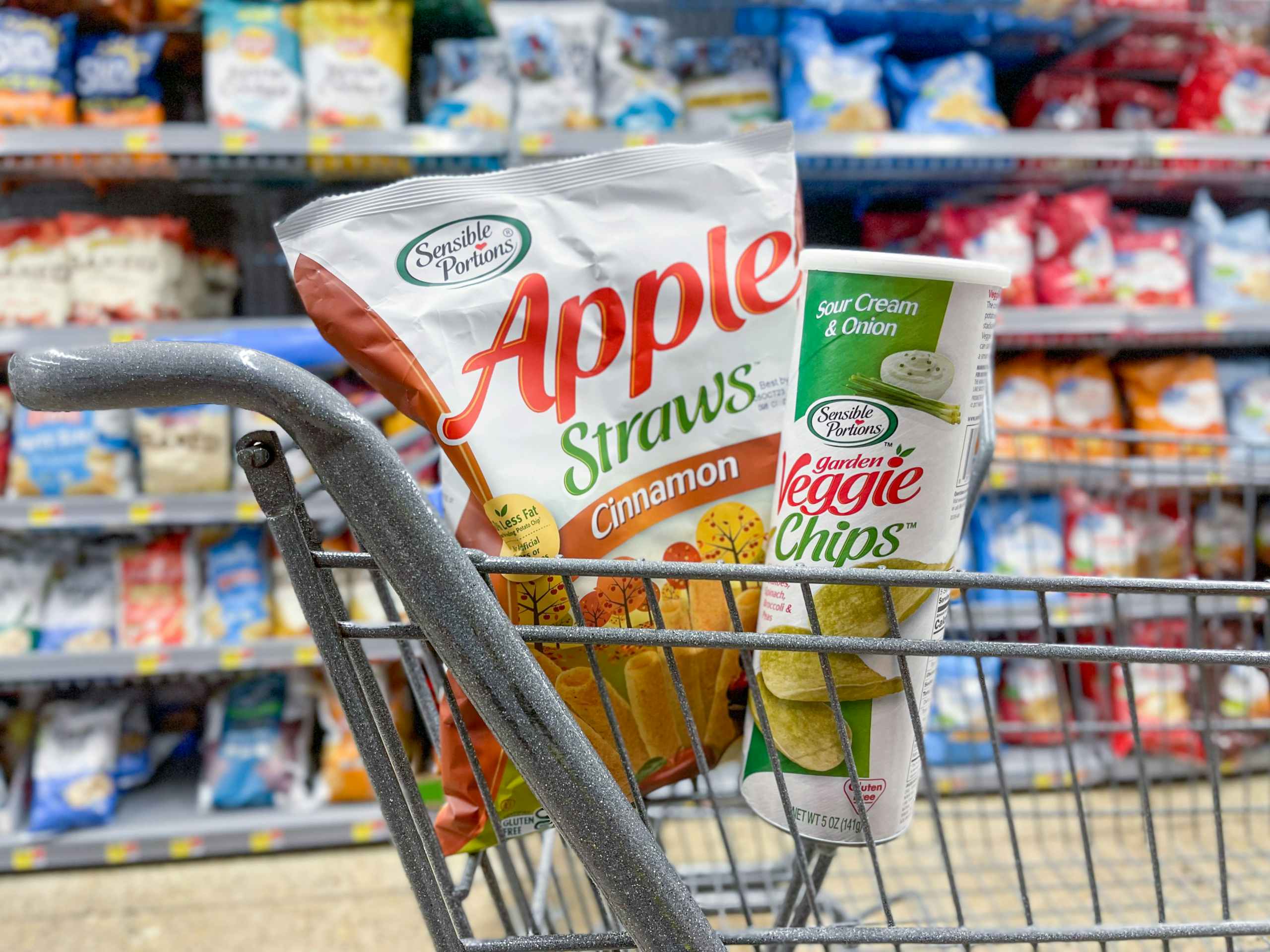 An Apple Straws bag and Veggie Chips can sitting in a store cart.
