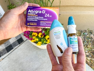 Someone holding different kinds of allergy medications at home