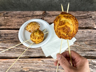 hand holding campfire cinnamon rolls with skewers