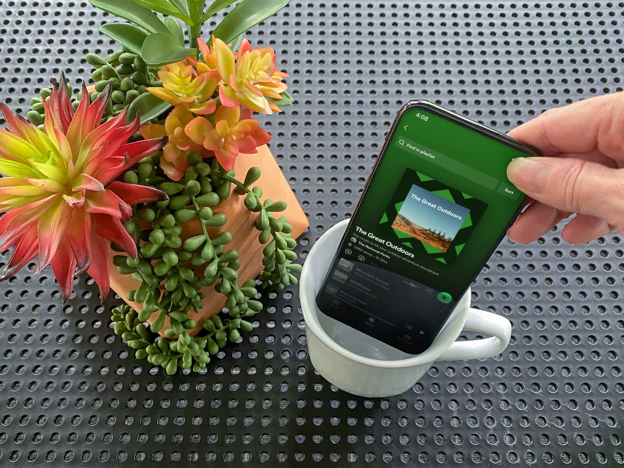 person placing a phone with spotify music playing into a coffee mug for sound amplification