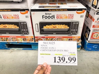 hand holding a sign for 139.99 ninja air fry oven