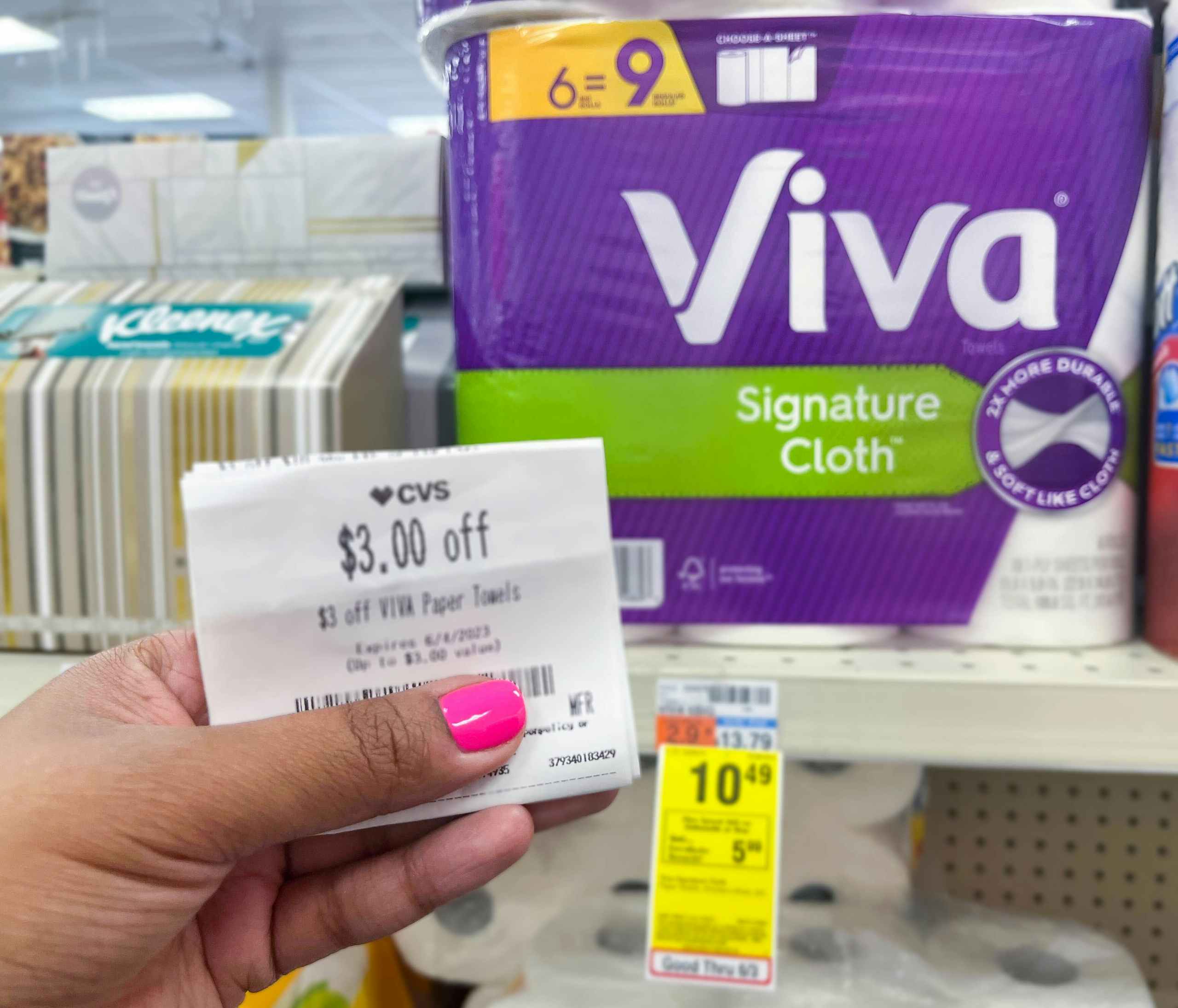 hand holding $3 Viva paper towel store coupon in front of Viva pack on shelf with sales tag underneath