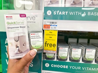 one CVS Health QuickServe dispenser base with bottle of adult multi-vitamin refill being held next to sales tag
