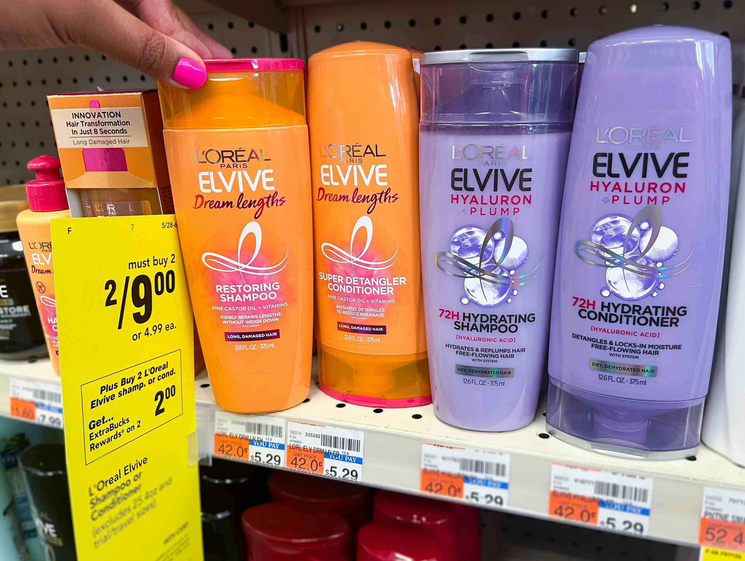 hand grabbing bottle of L'Oreal Elvive shampoo next to sales tag