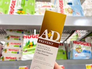 a box of a & d ointment being held in front og huggies boxes in store