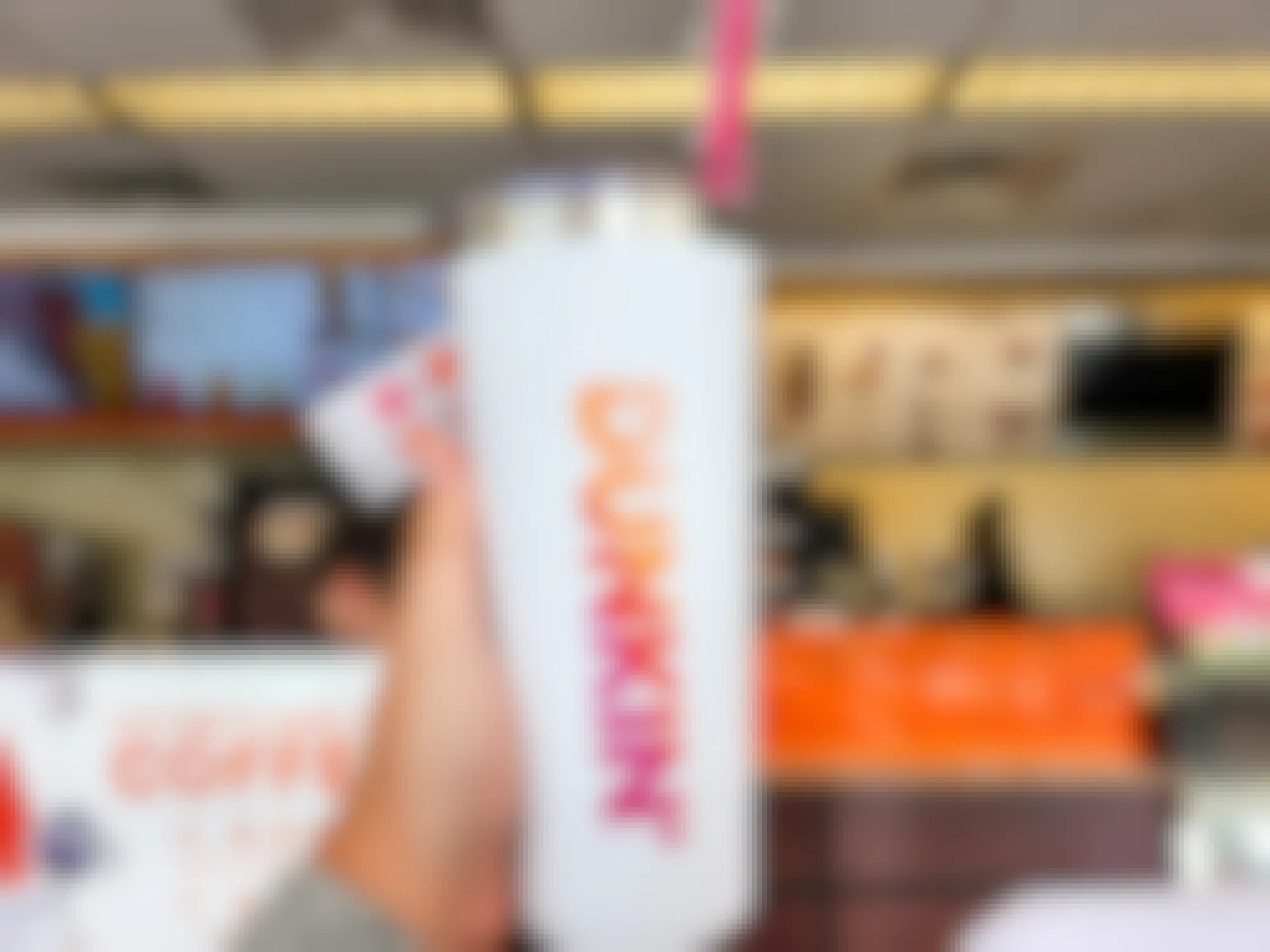 Someone holding up a Dunkin tumbler with a straw