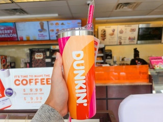 Someone holding up a Dunkin tumbler with a straw