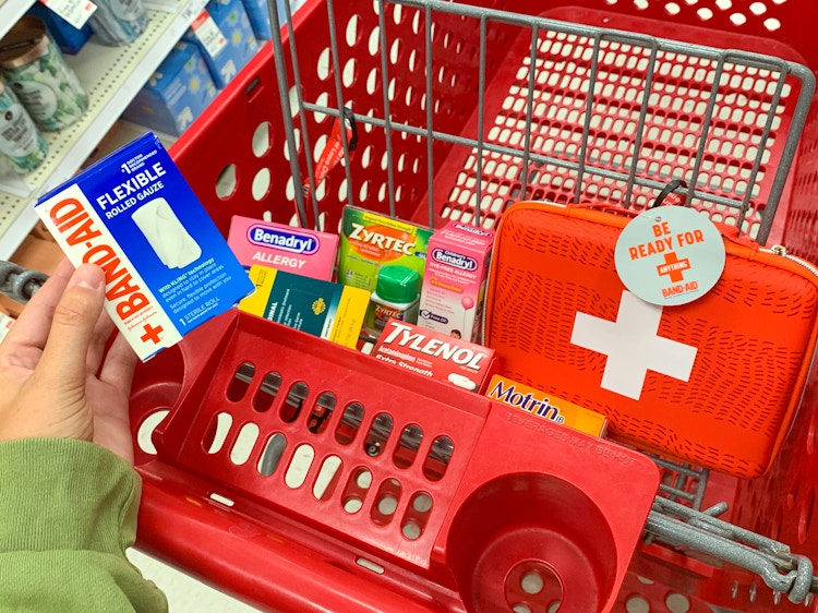 a person holding bandaids in front of a cart full of items from target