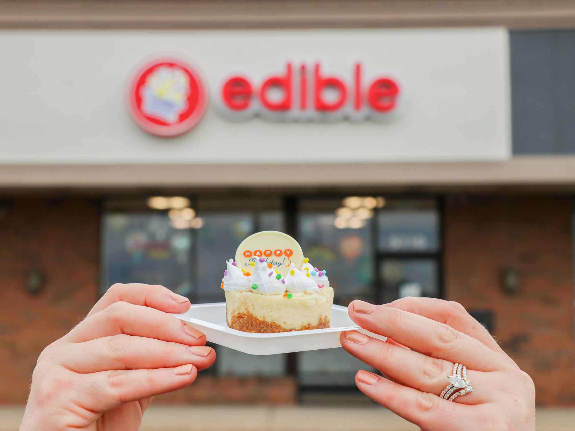 a person holding up a birthday treat outside of edible arrangements 