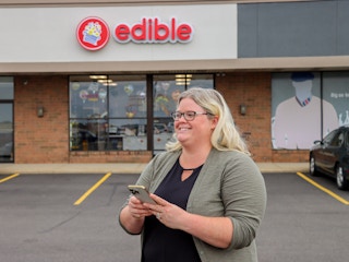 a person looking at their phone outside of edible arrangements