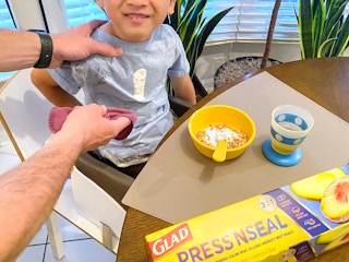 person wiping yogurt from a diy bib made from glad press'n seal wrap