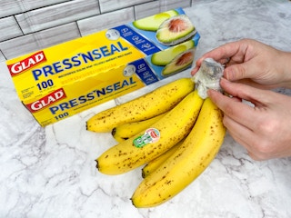 Someone using Glad Press N' Seal to keep a bunch of bananas fresh