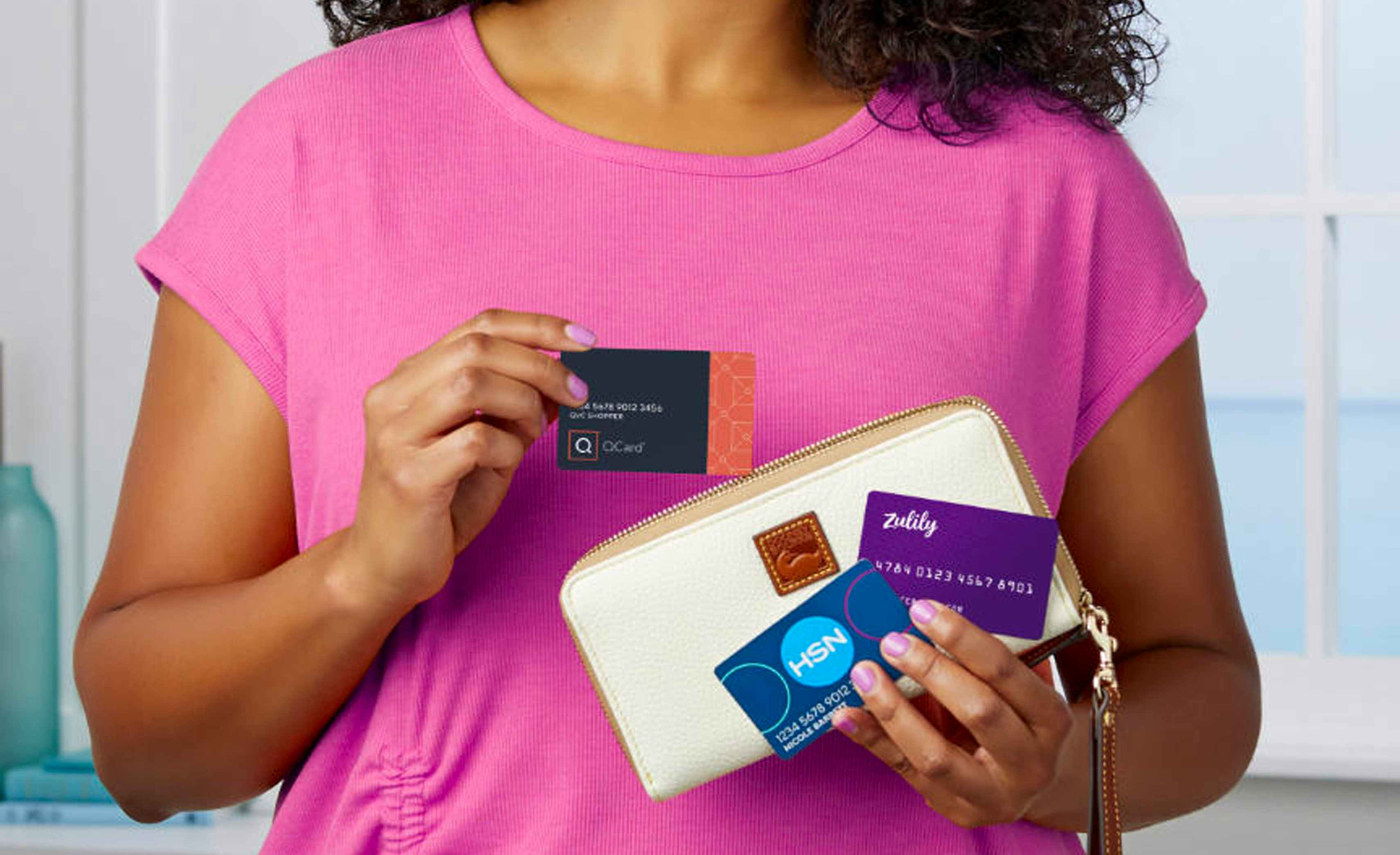 Person holding three different credit cards with their wallet