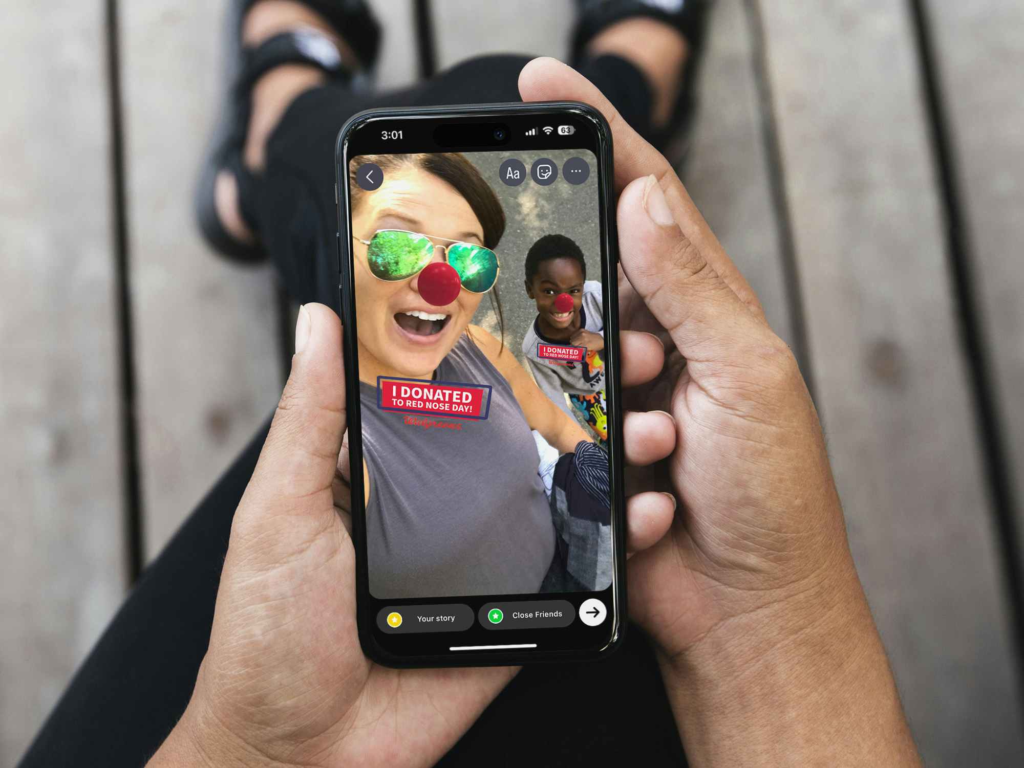 A phone showing a selfie taken of a woman and her son with the Red Nose Day filter on