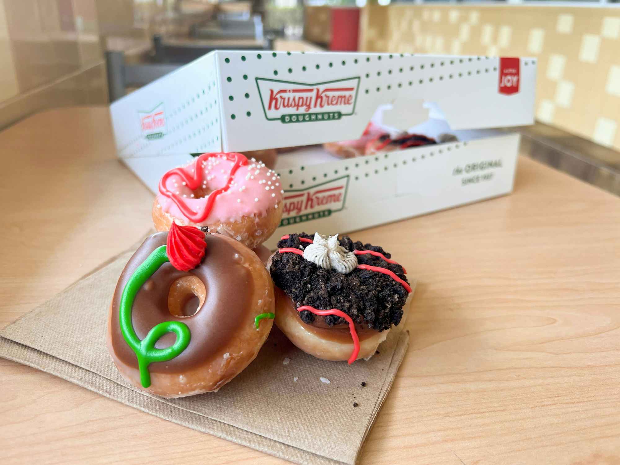Some Mother's Day Krispy Kreme doughnuts sitting on a napkin next to a Krispy Kreme box