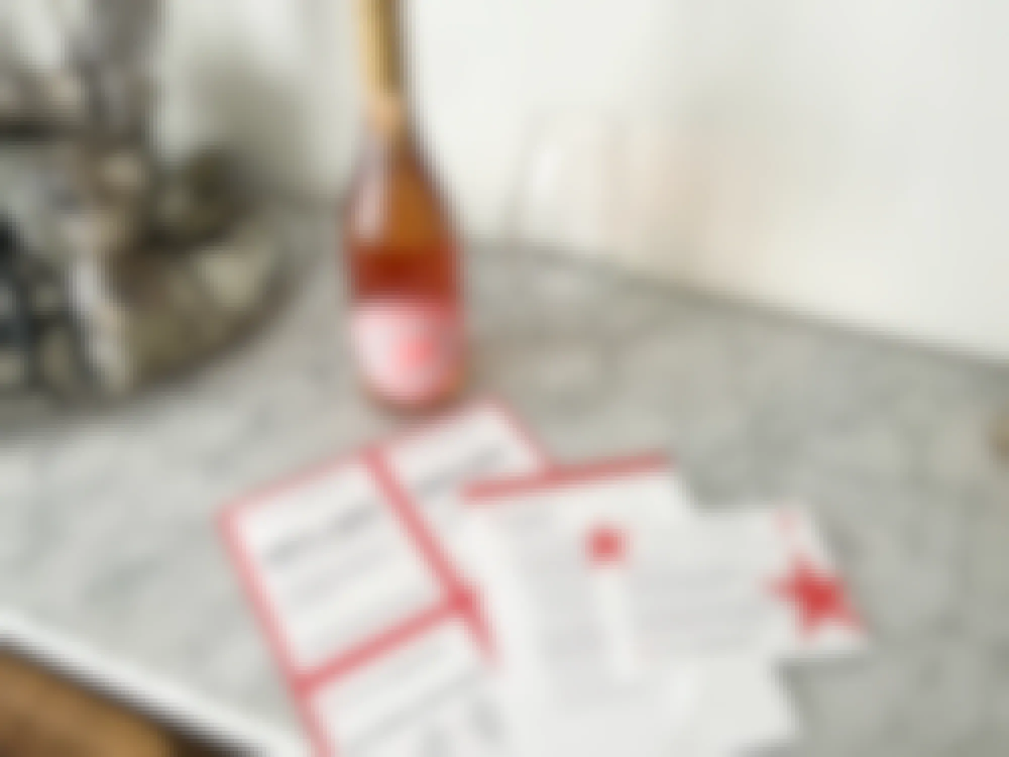A bottle of wine on a counter with some Macy's Wine Shop coupons and information cards