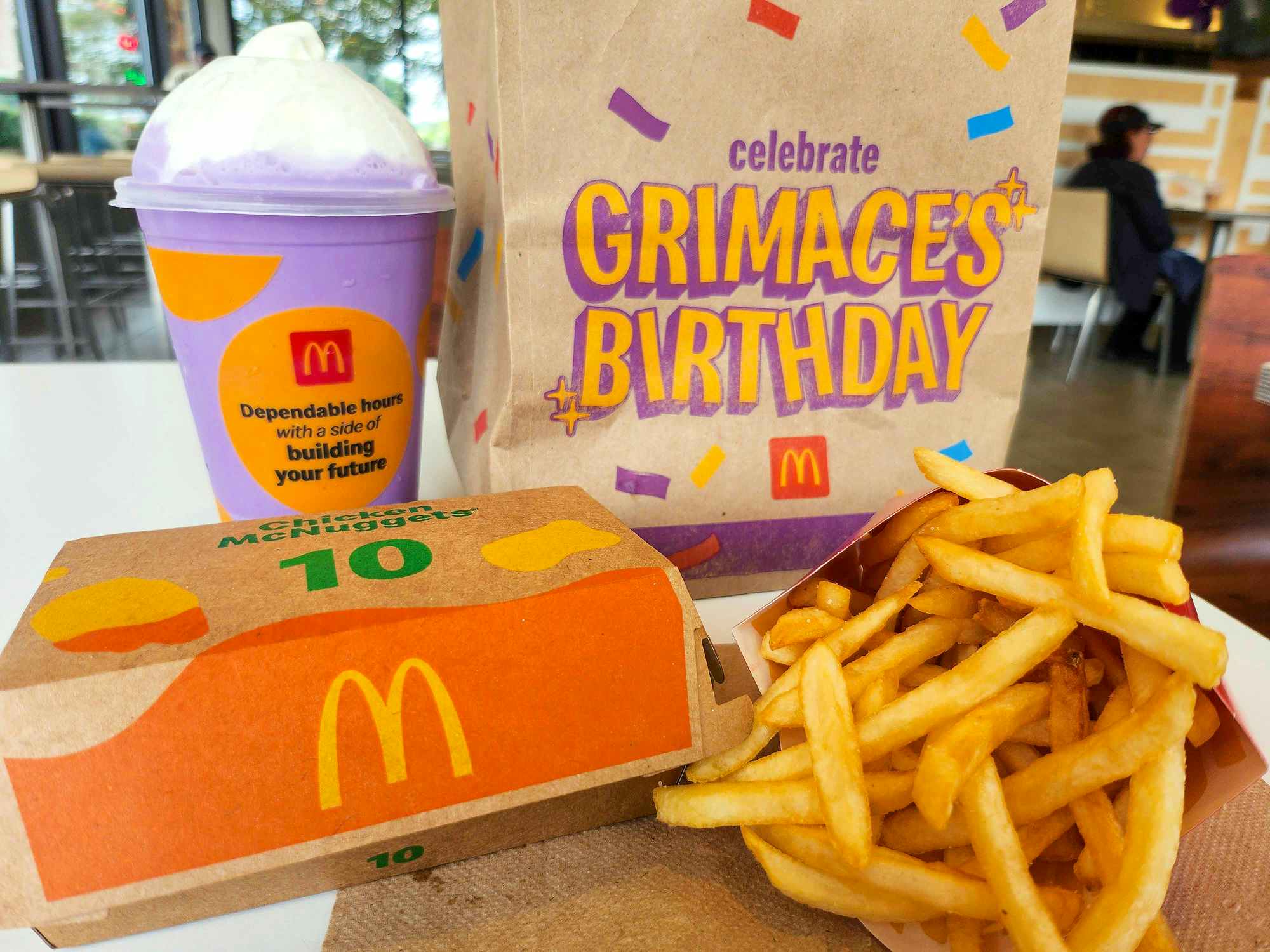 mcdonalds grimaces birthday meal shake, mcnuggets, fries, and bag on table