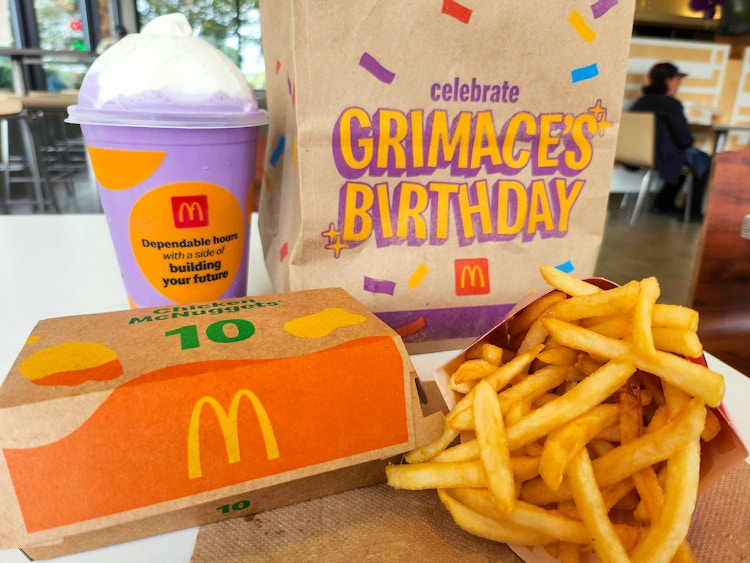 mcdonalds grimaces birthday meal shake, mcnuggets, fries, and bag on table