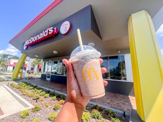 a hand holding an oreo frappe in front of a mcdonalds sign