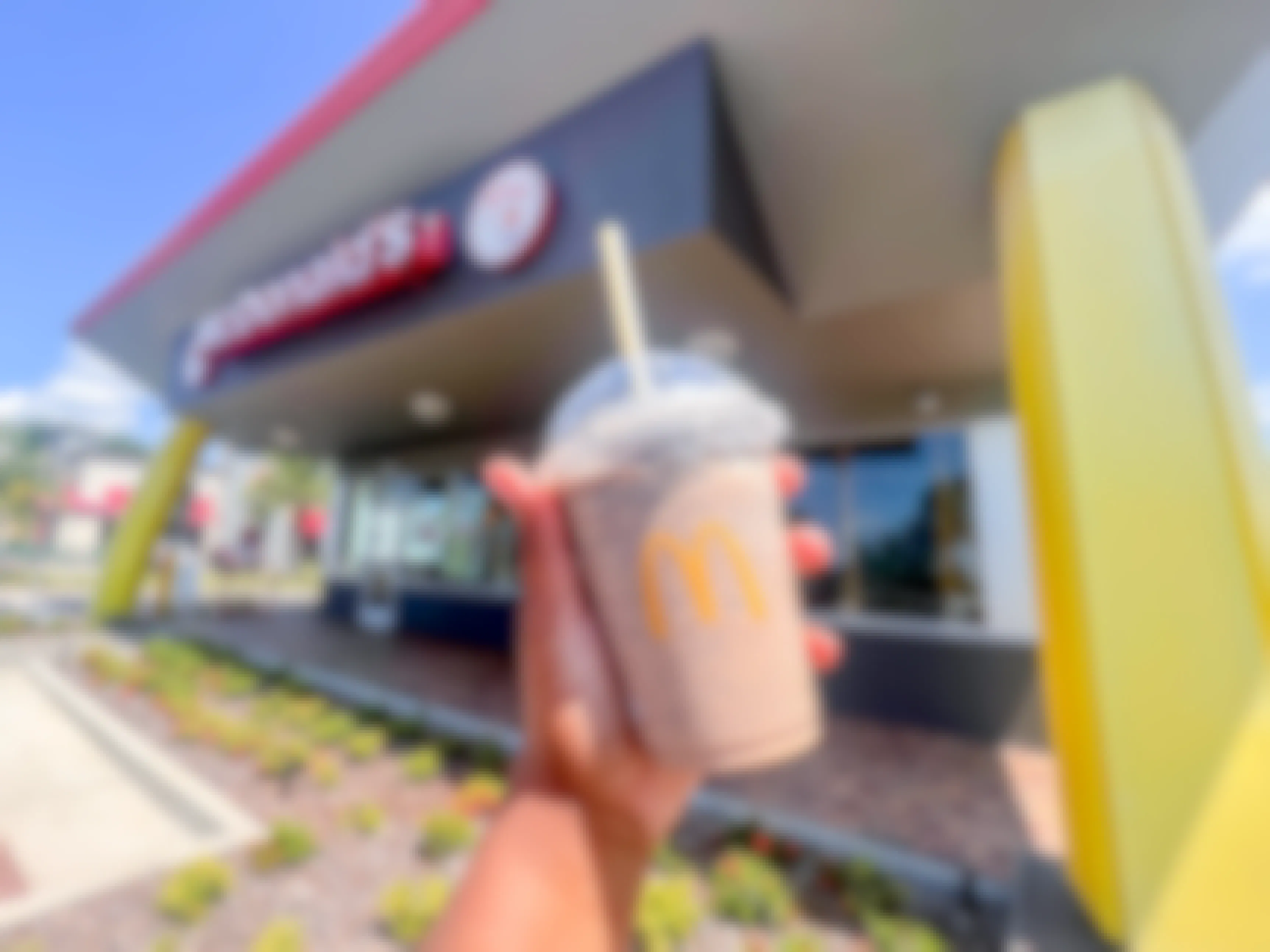 a hand holding an oreo frappe in front of a mcdonalds sign