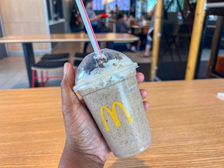a hand holding a mcdonalds frappe in a mcdonalds restaurant