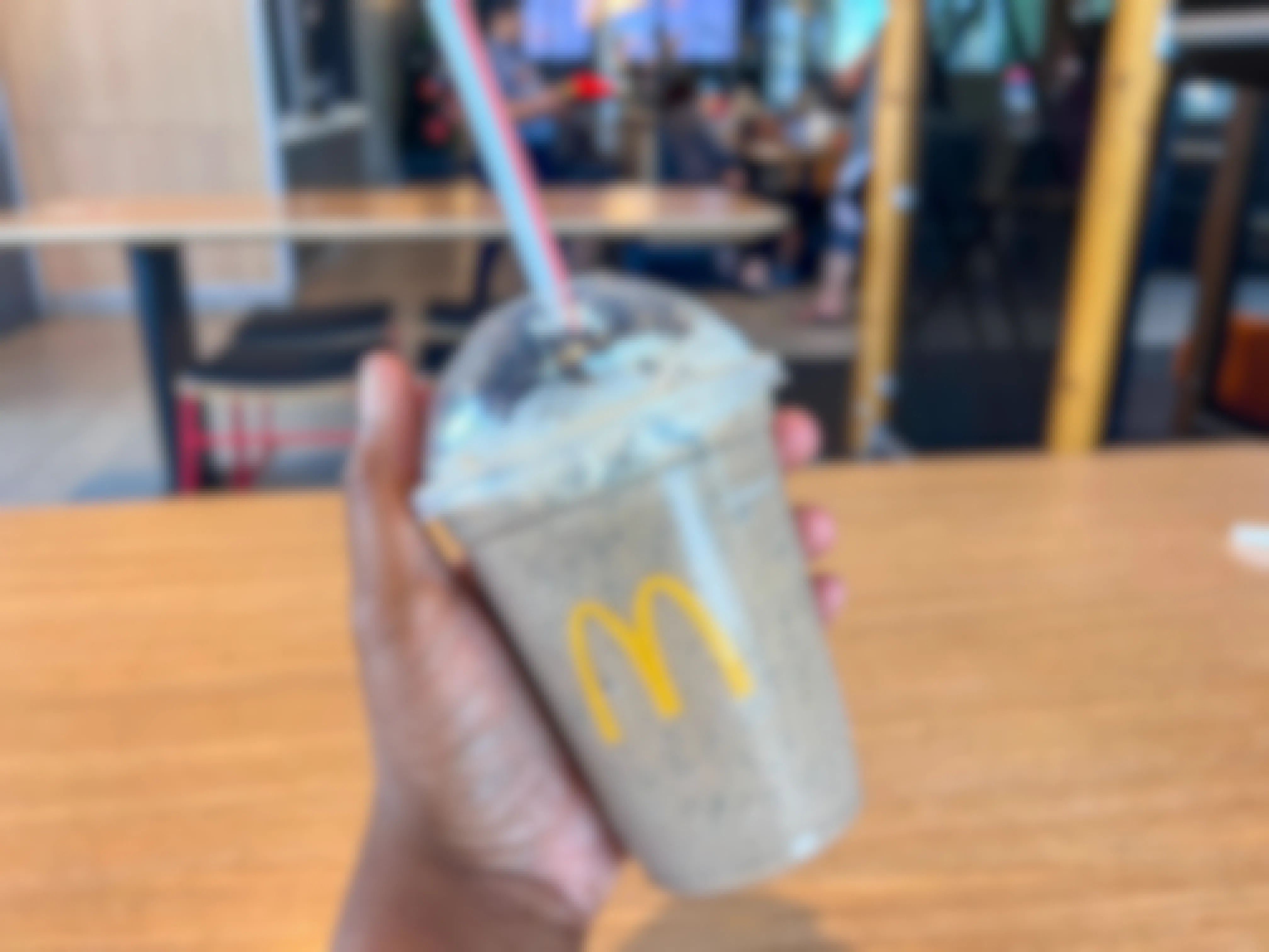 a hand holding a mcdonalds frappe in a mcdonalds restaurant 