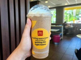 person holding a mcdonalds oreo frappe in restaurant