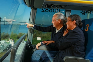 Two people riding on a Megabus pointing out the window