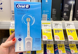 hand holding an oral-b rechargeable toothbrush next to a walgreens sale tag