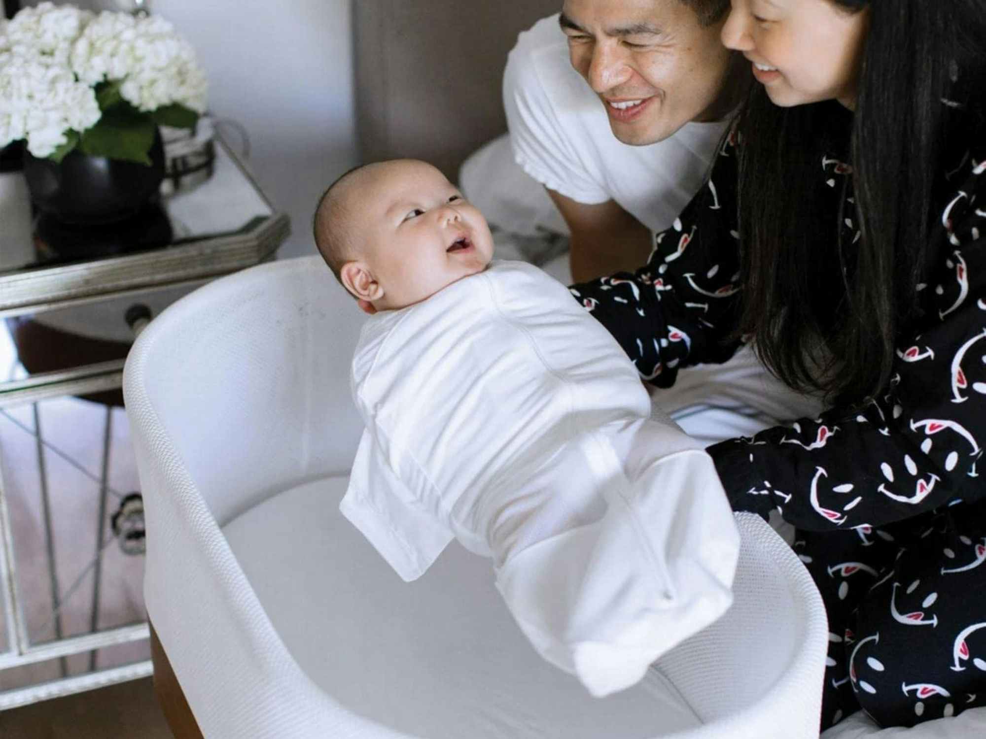 Parents placing their baby into a SNOO Bassinet