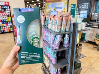a hand holding color changing cold cups in front of a coffee display