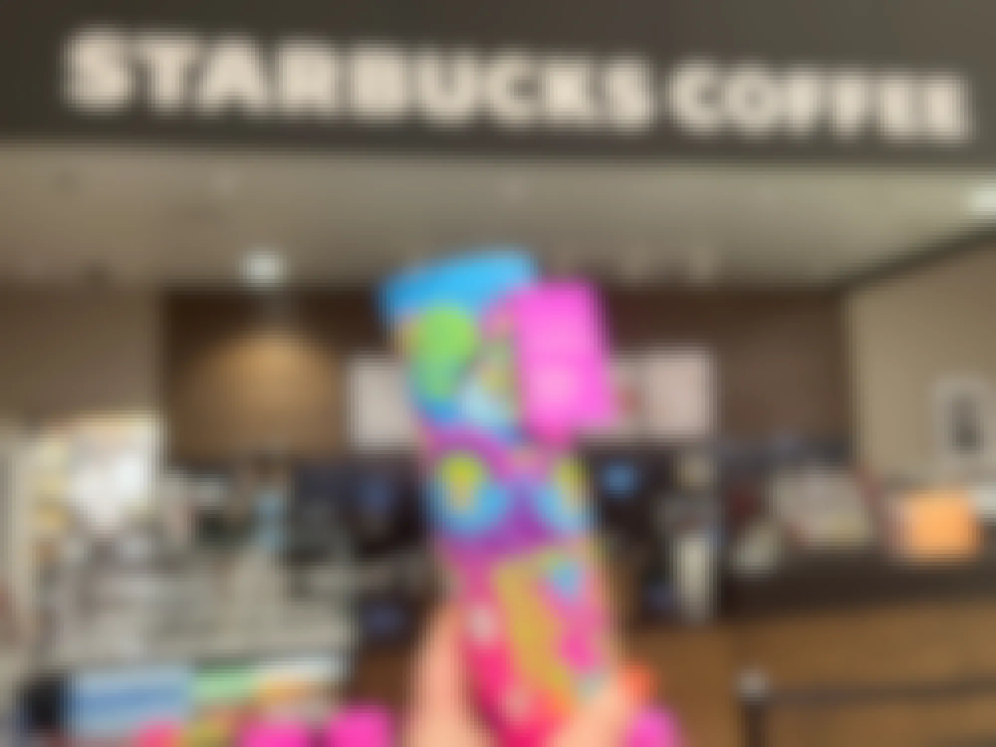 Someone holding up a Starbucks Pride cup inside a Starbucks