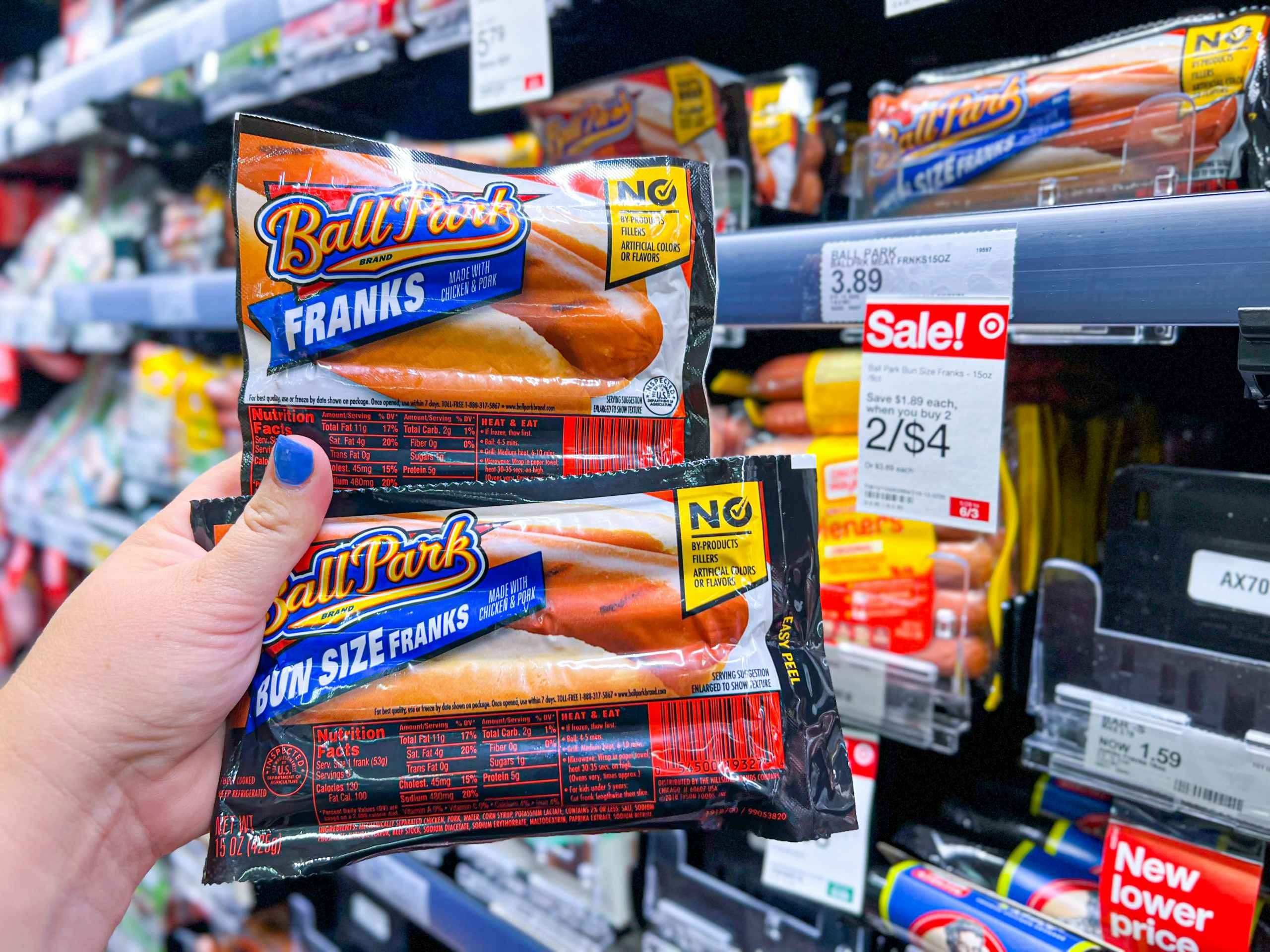 hand holding two packs of Ball Park Franks next to sales tag