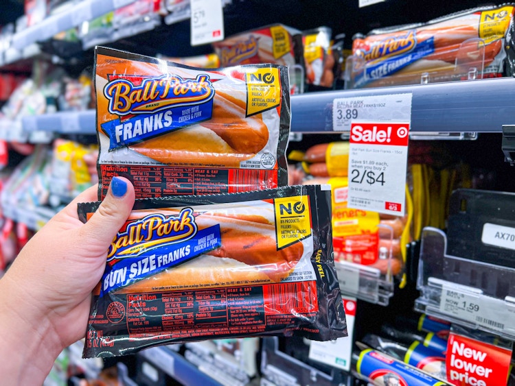 hand holding two packs of Ball Park Franks next to sales tag