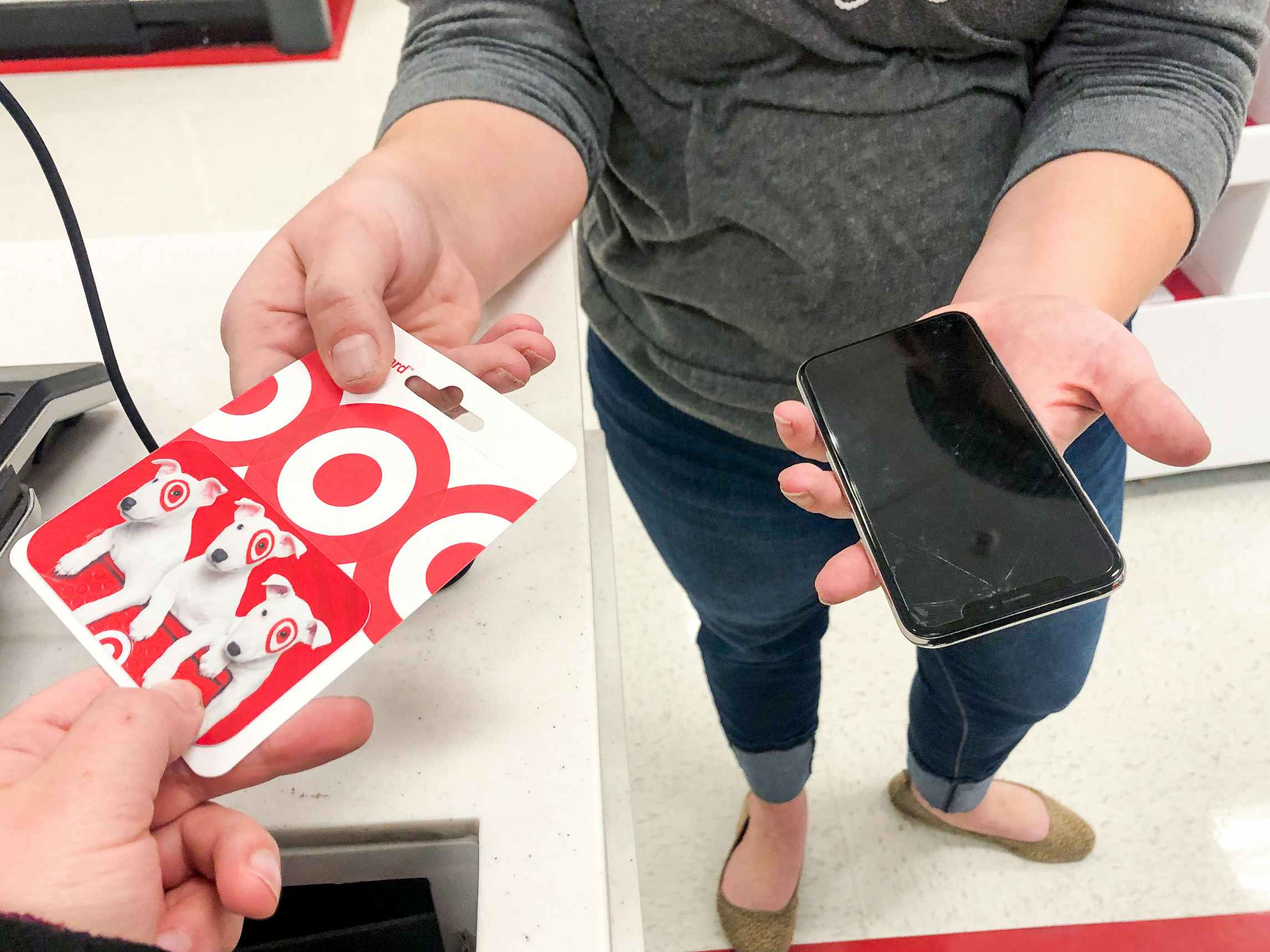 a woman trading in her old android phone to target's trade-in program for a gift card
