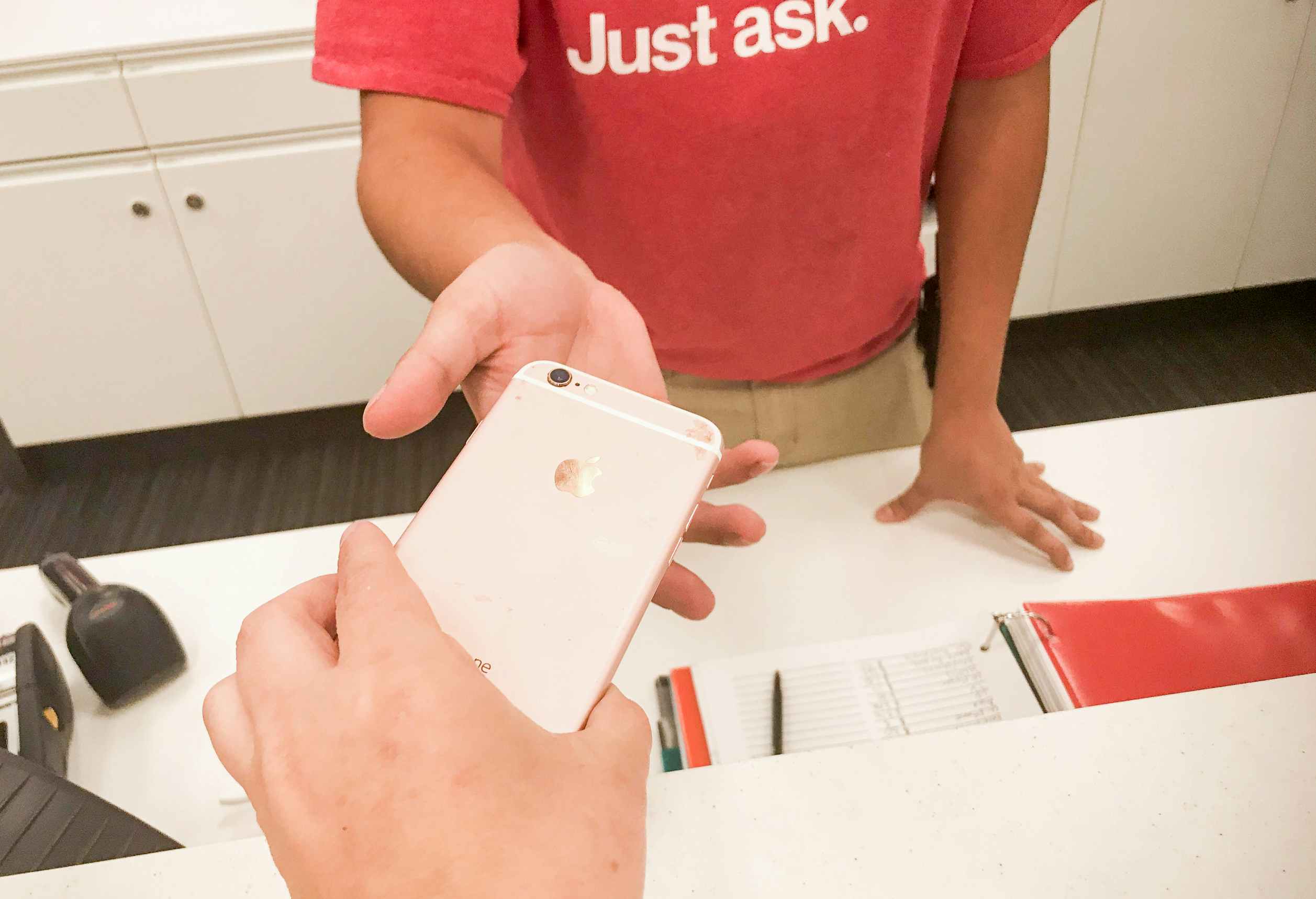 A woman handing an old iphone to a target sales associate