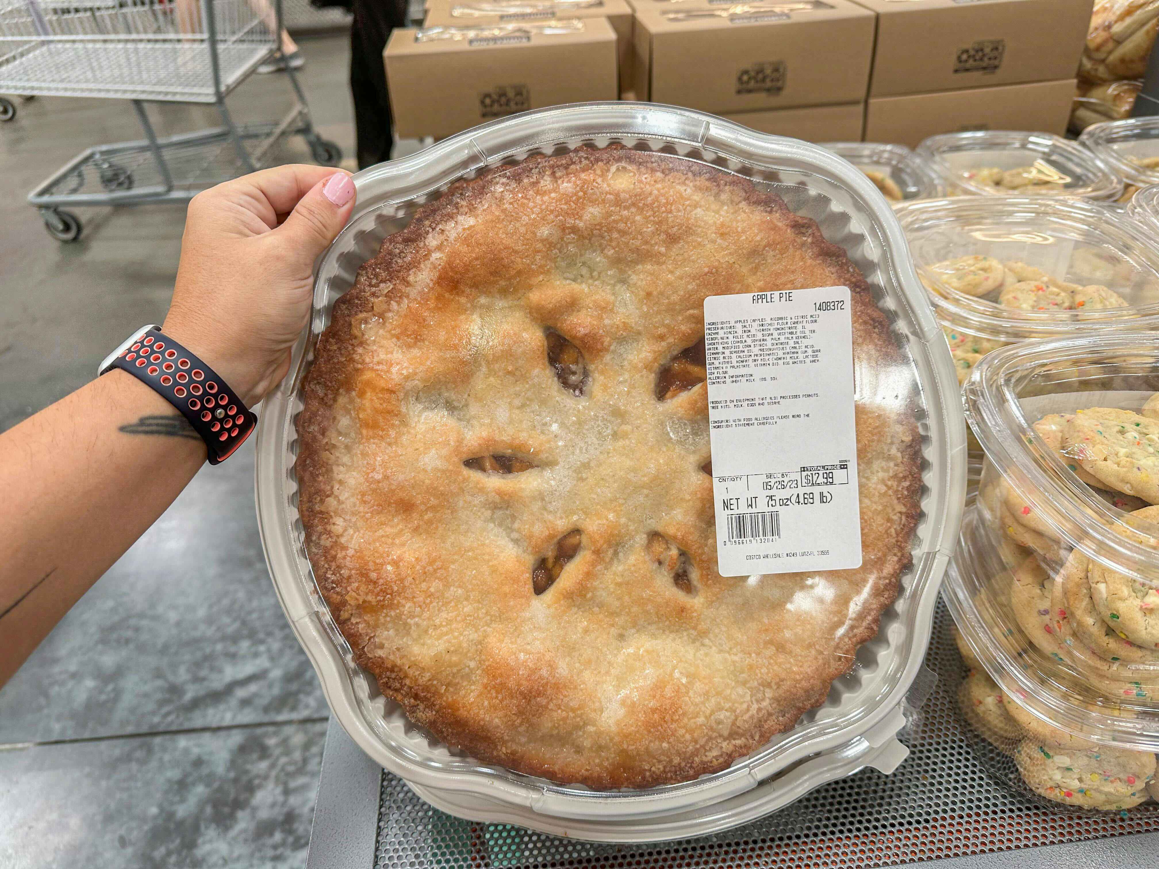 a person holding up an apple pie at costco